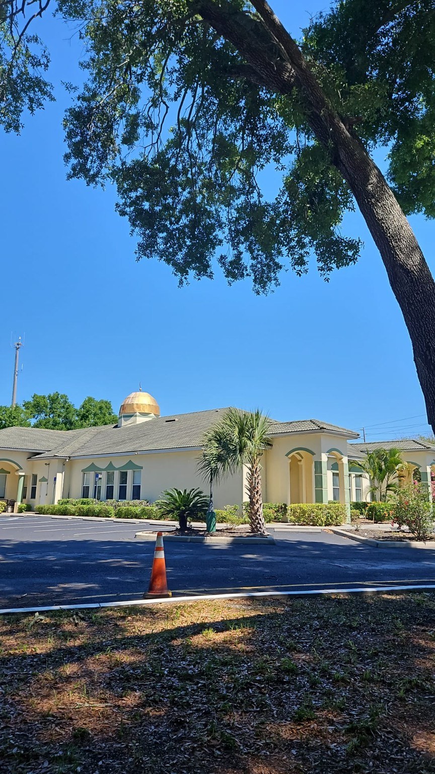 ICOPC masjid beneath trees and a clear blue sky